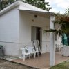 Bungalow bianco con veranda, sedie e palma davanti.