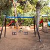 Area giochi esterna con altalene e scivoli.