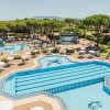 Piscine a forma di stella con ombrelloni bianchi e vegetazione.