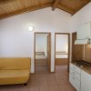 Interno con divano giallo, cucina e due porte alla camera da letto.