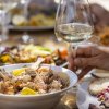 Tavola imbandita con piatti di pesce e bicchieri di vino.