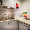 Cucina compatta con lavello, piano cottura, frigo e mosaico alle spalle.