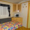 Stanza con letto colorato, TV su mobile e finestra con tenda scura.