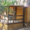 Casetta in legno semplice con veranda, sedie e tavolo esterni.