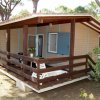 Bungalow in legno con veranda e vegetazione intorno.