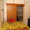 Tavolo con tovaglia a girasoli, fiori rossi, porta scorrevole e TV.