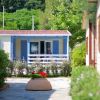 Un bungalow con persiane blu tra alberi e cespugli fioriti.