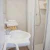 Bagno con lavabo, doccia e asciugamani su una mensola.