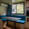 Sala con tavolo, sedute blu, finestra, TV e condizionatore.