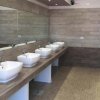 Un bagno moderno con sei lavandini bianchi su un lungo bancone.