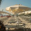 Spiaggia sabbiosa con lettini e ombrelloni bianchi.
