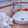 Lavabo moderno, con asciugamani bianchi e fiori rossi.