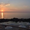 Tramonto sul mare con ombrelloni bianchi sulla spiaggia.