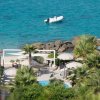 Spiaggia con palme e gommone in mare azzurro.