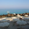 Spiaggia con ombrelloni beige e mare calmo.