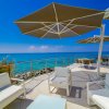 Terrazza sul mare con sedie bianche e ombrelloni grigi.
