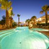 Piscina illuminata di sera, circondata da palme.
