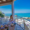 Donna seduta su un balcone vista mare con colazione.