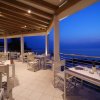 Una terrazza con tavoli apparecchiati al tramonto sul mare.
