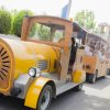 Trenino giallo con persone a bordo su una strada.