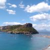 Spiaggia con isola rocciosa e ombrelloni.