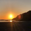 Tramonto sul mare con colline all'orizzonte.