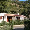 Casa con veranda e cespugli verdi davanti.