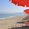 Spiaggia sabbiosa con ombrelloni arancioni.