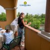 Famiglia su una terrazza, due adulti con bicchieri di vino, due bambini seduti a un tavolo.