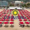 Una spiaggia affollata con file ordinate di ombrelloni rossi e lettini.