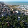Veduta dall'alto di una città costiera con un porto turistico e alberi.