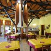 Interno di un ristorante con tavoli apparecchiati, soffitto in legno e travi nere.