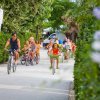 Gruppo di persone in bicicletta su una strada circondata da vegetazione.