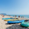 Tavole da surf su una spiaggia affollata con persone che nuotano nel mare.
