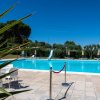 Piscina con scivolo e ombrelloni, cielo blu.