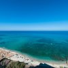 Spiaggia con ombrelloni e mare cristallino visto dall'alto.