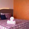Letto matrimoniale con copriletto rosa e cuscini colorati.