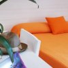 Letto arancione con pianta e cappello su un tavolo.