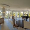 Una sala luminosa con tavoli, sedie e grandi finestre.