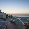 Terrazza con vista mare al tramonto e struttura conico-arancione.