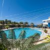 Piscina con palme, sedie a sdraio e costruzione a forma di cono.