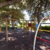Parco giochi ombreggiato con scivolo e altalena.