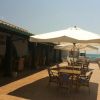 Terrazza con tavoli, sedie e ombrelloni vicino al mare.