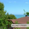 Vista mare con tetto di un gazebo e pini.