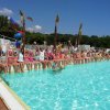 Bambini seduti sul bordo di una piscina alzando le braccia.