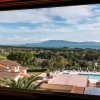 Vista panoramica su una piscina, tetti di case, paesaggio verde e mare in lontananza.