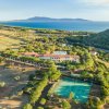 Vista aerea di un resort con campi da tennis vicino al mare.