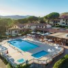 Piscina all'aperto circondata da lettini e ombrelloni, con edifici residenziali sullo sfondo.
