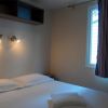 Una stanza con letto matrimoniale, due luci a parete accese e finestra con tenda a righe.