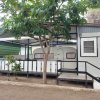 Una casa mobile con una veranda, parzialmente coperta, e un grande albero davanti.